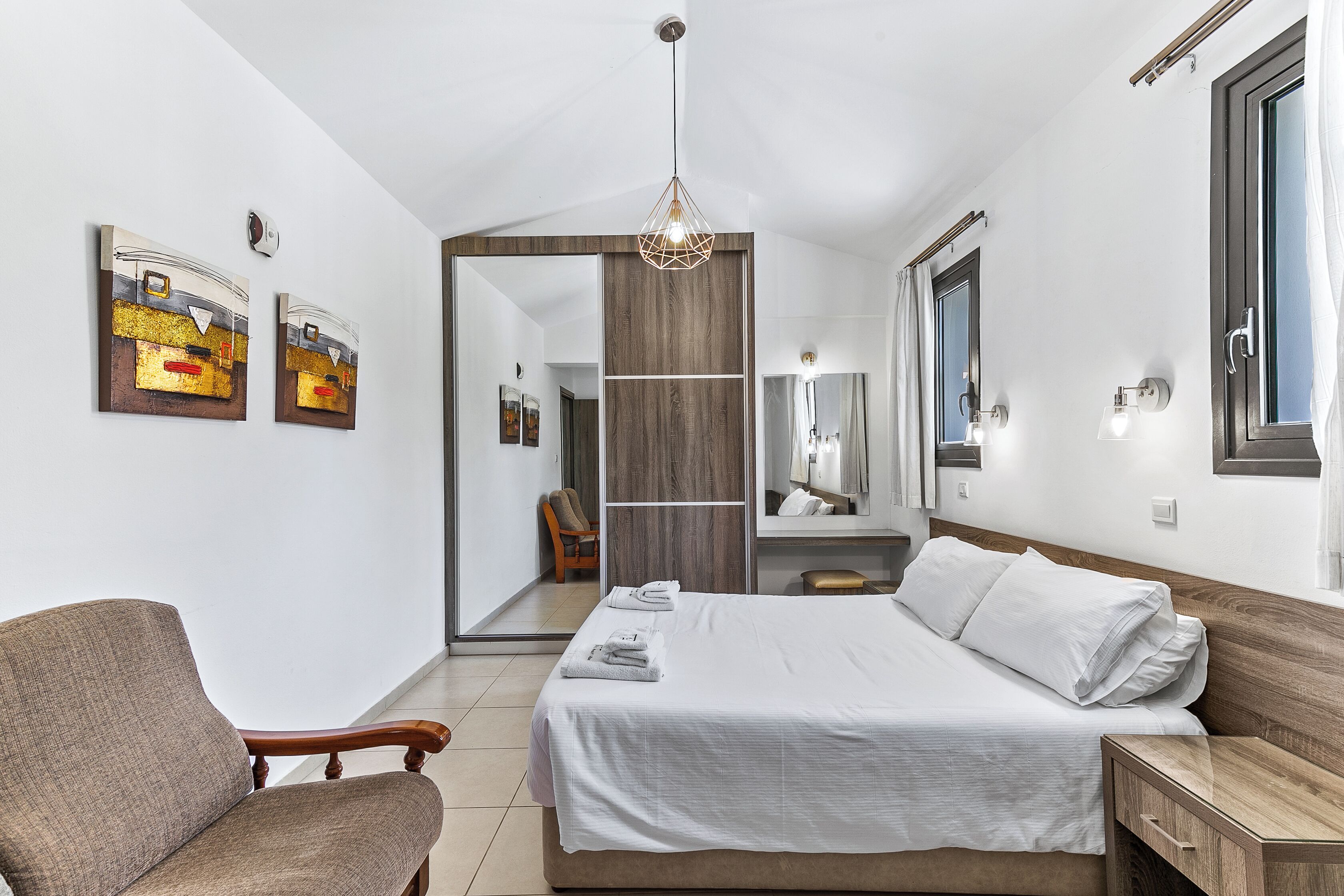 Une chambre à coucher moderne avec un lit, une chaise, une armoire et un miroir.