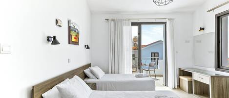 Une chambre d’hôtel moderne avec deux lits, un bureau et une grande fenêtre donnant sur un immeuble.