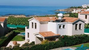 A coastal residential area with modern white houses, a swimming pool, and a view of the sea. - Platzia Beach Villas (Kissonerga)