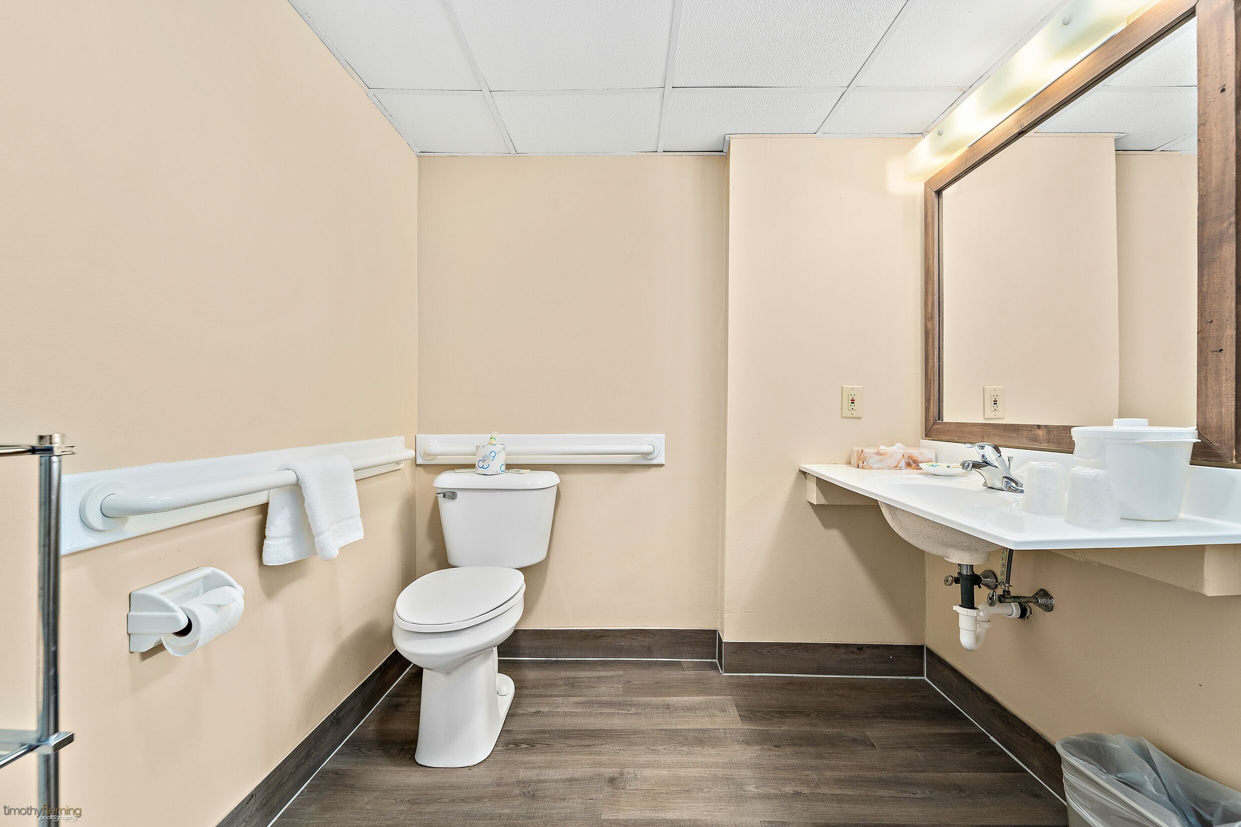 Une salle de bain équipée de toilettes, d’un lavabo, d’un miroir et d’un porte-serviettes.