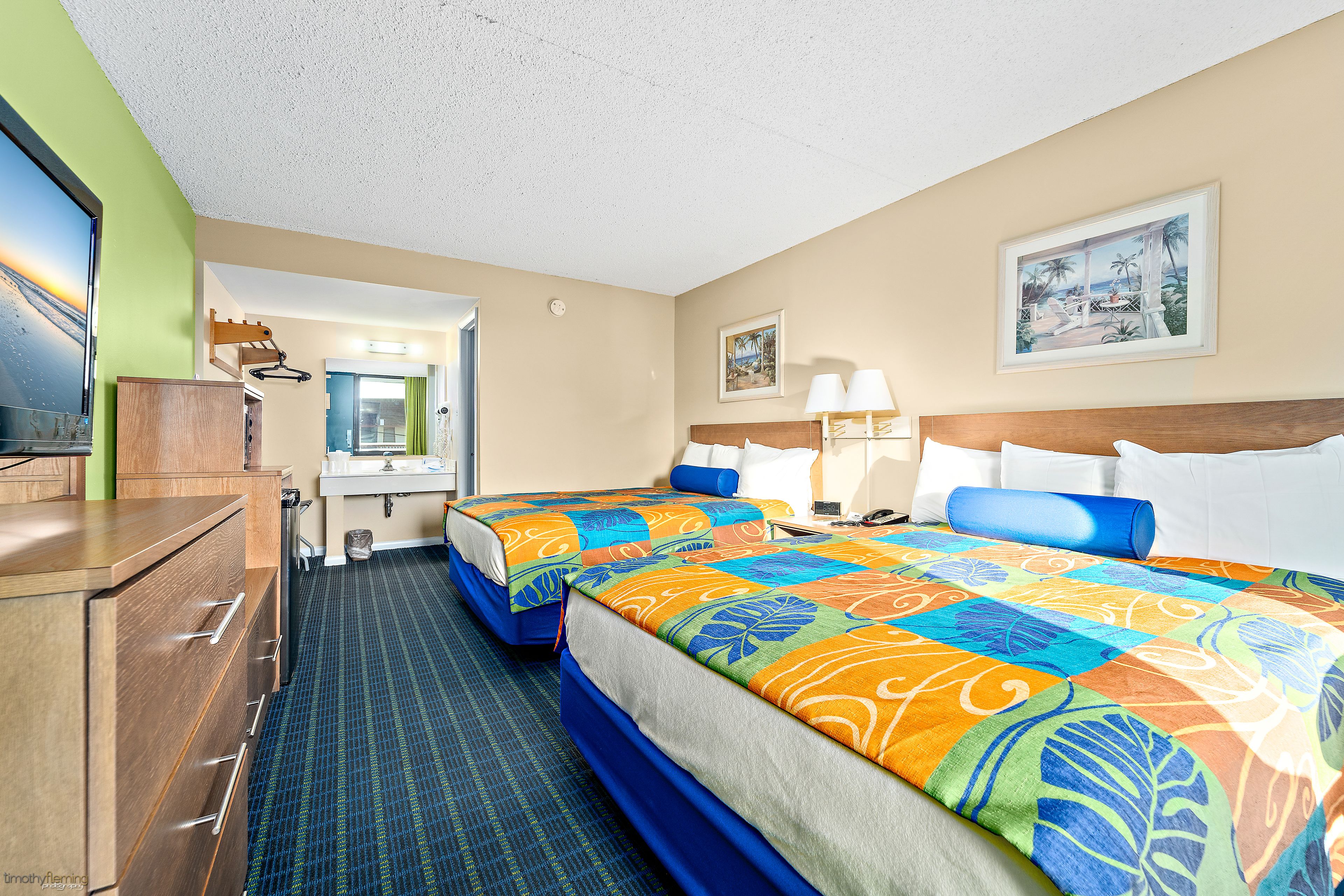 A hotel room with two beds, a bathroom, and a view of the beach.