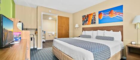 Habitación de hotel con una cama grande, televisión, escritorio y baño visible a través de una puerta abierta.