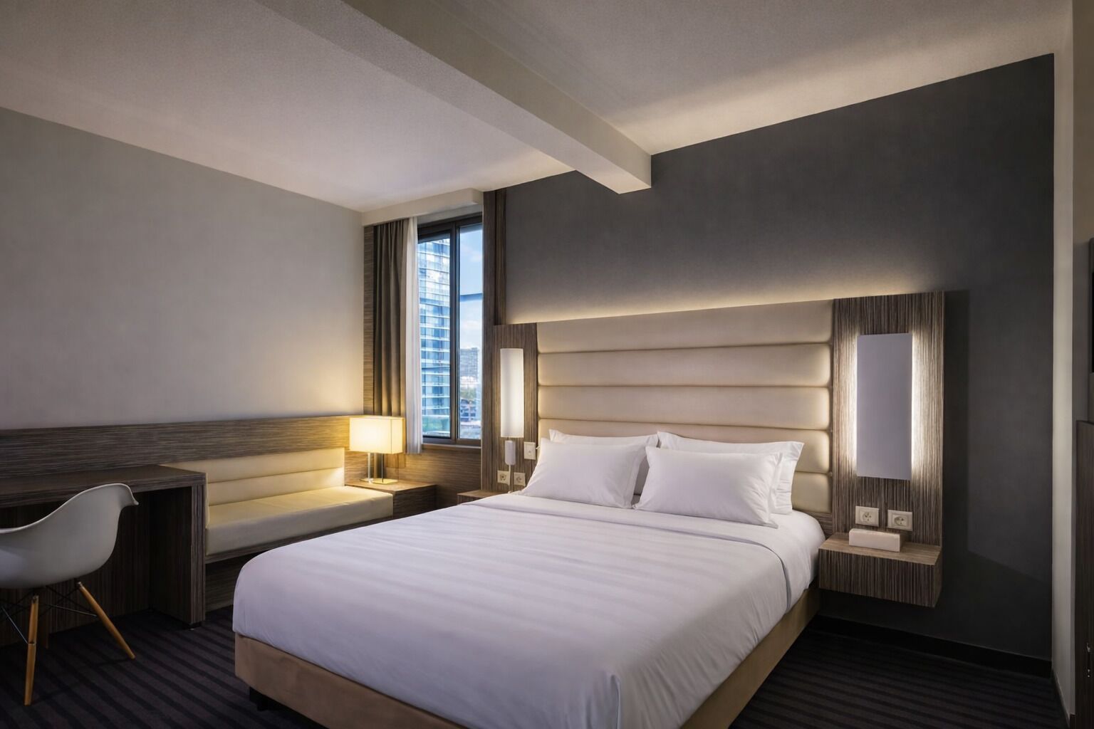A modern hotel room with a large bed, a desk, and a chair.