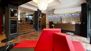 Un vestíbulo de hotel con diseño moderno, que cuenta con una escalera, un mostrador de recepción y zonas de estar.