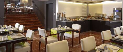 A modern dining area with a staircase leading to a dining room, a buffet setup, and a coffee machine.