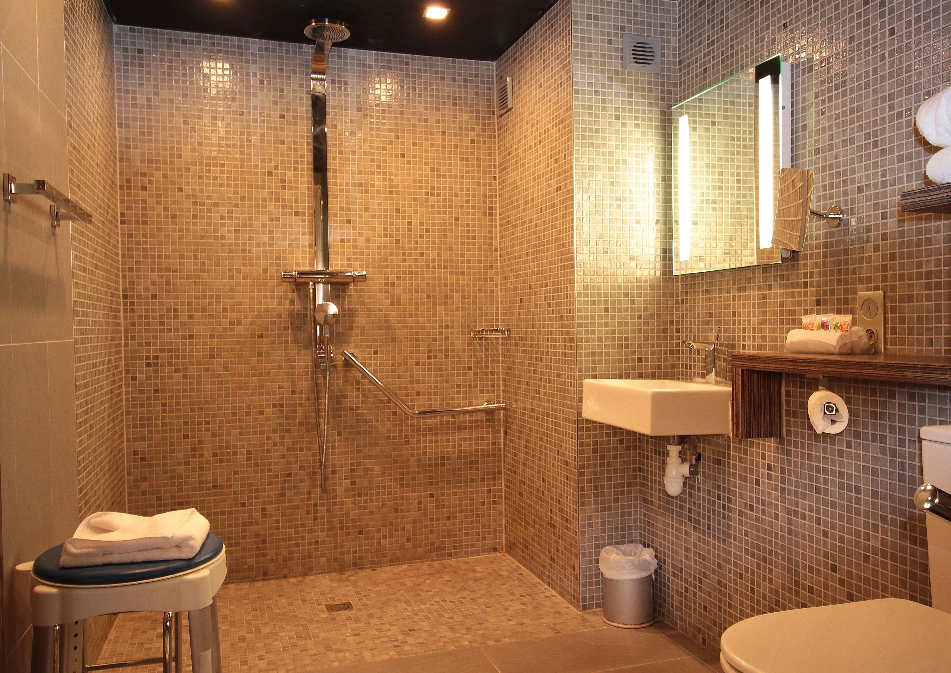 A bathroom with a shower, toilet, sink, and a mirror.