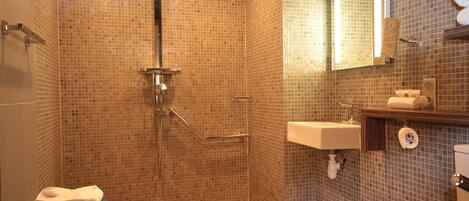 A bathroom with a shower, toilet, sink, and a mirror.