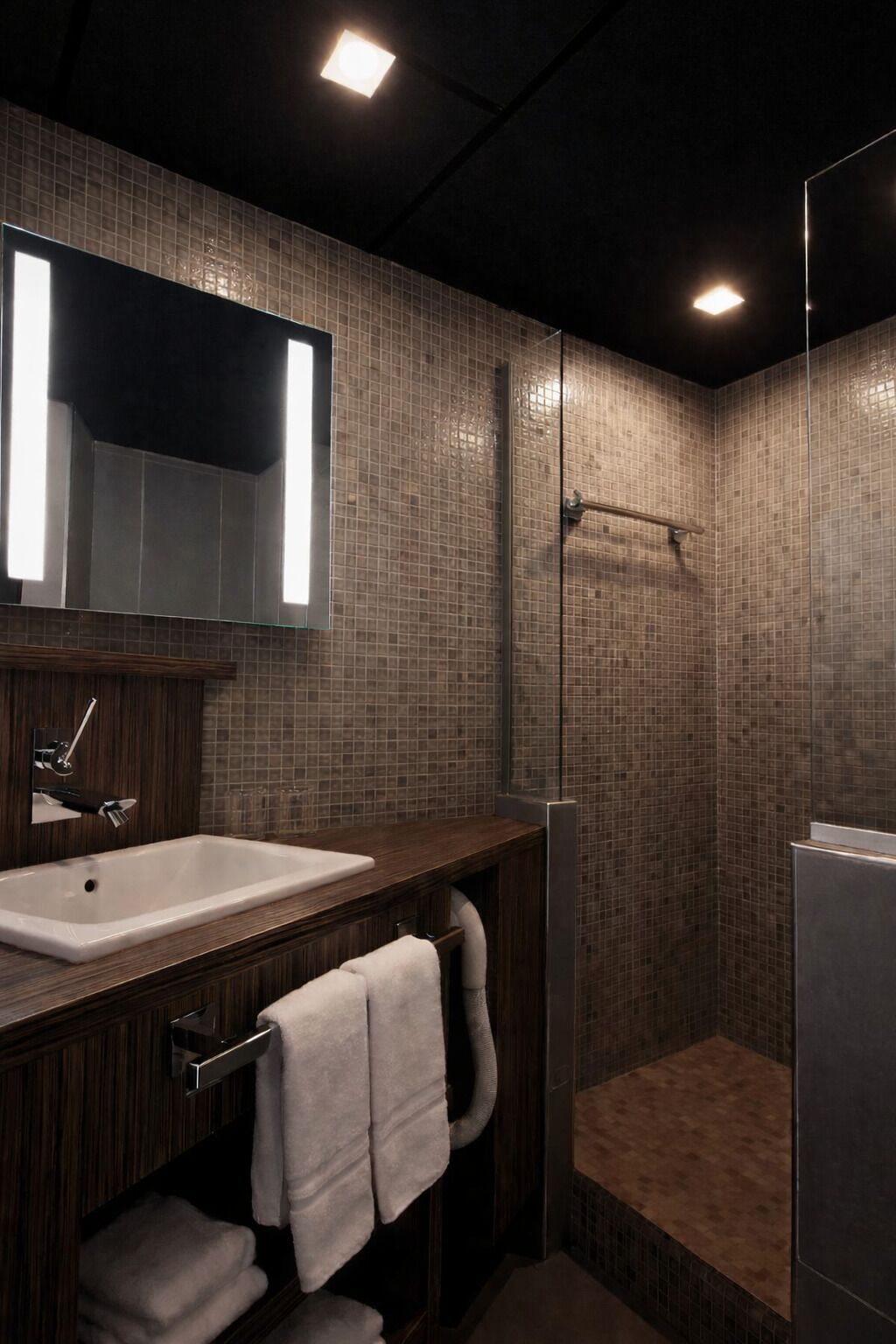 A modern bathroom with a large mirror, a sink, and a shower area.