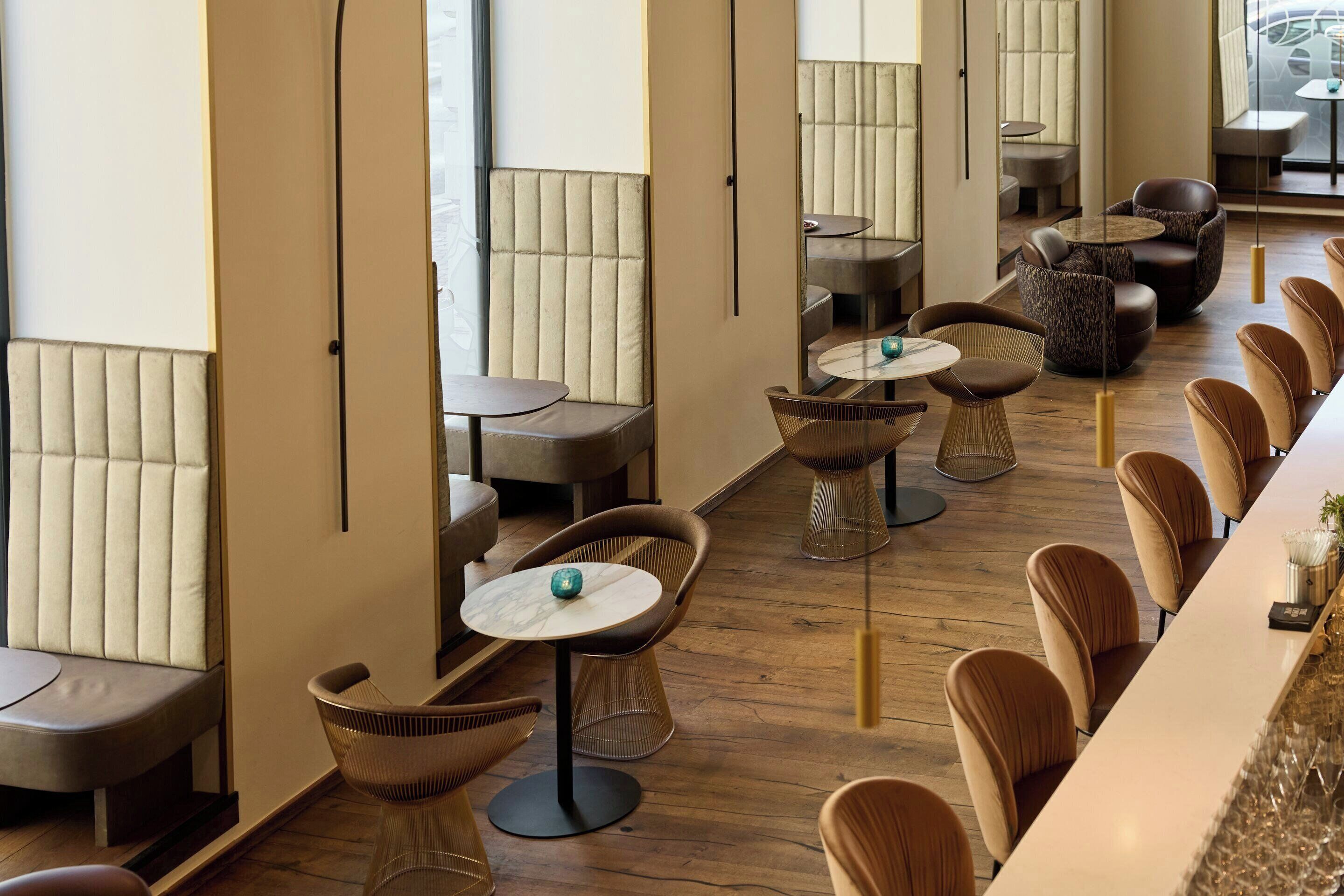 Un interior moderno con arreglos de asientos, mesas y una zona de bar.