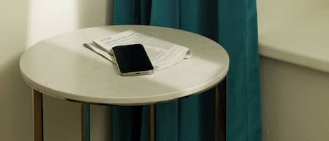 Uma pequena mesa redonda com um smartphone e um jornal.