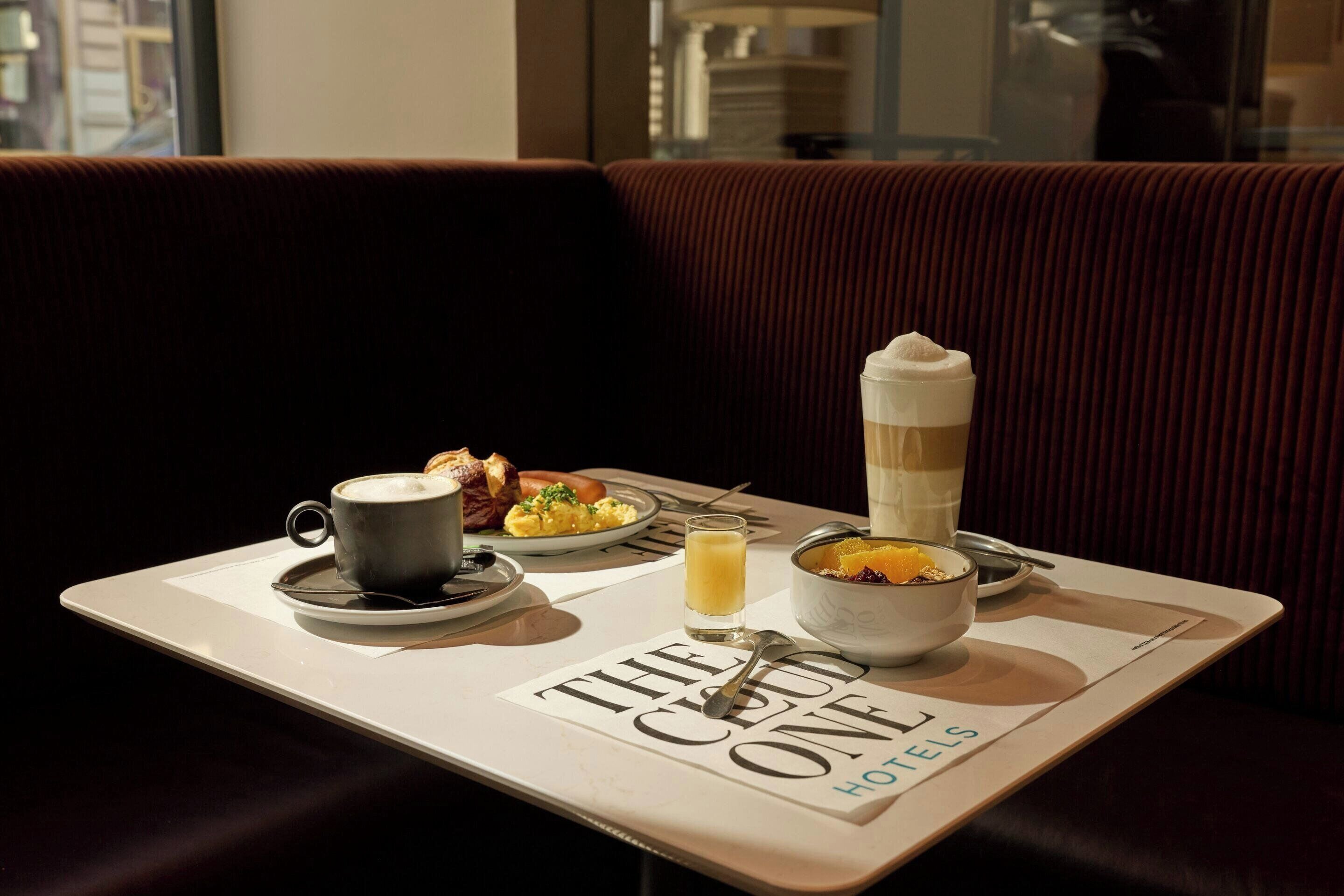 Bandeja de café da manhã com café, ovos mexidos e suco de laranja sobre uma mesa em um hotel.