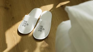Ein Paar weiße Slipper mit dem Aufdruck 'THE CLOUD ONE' auf Holzdielen.
