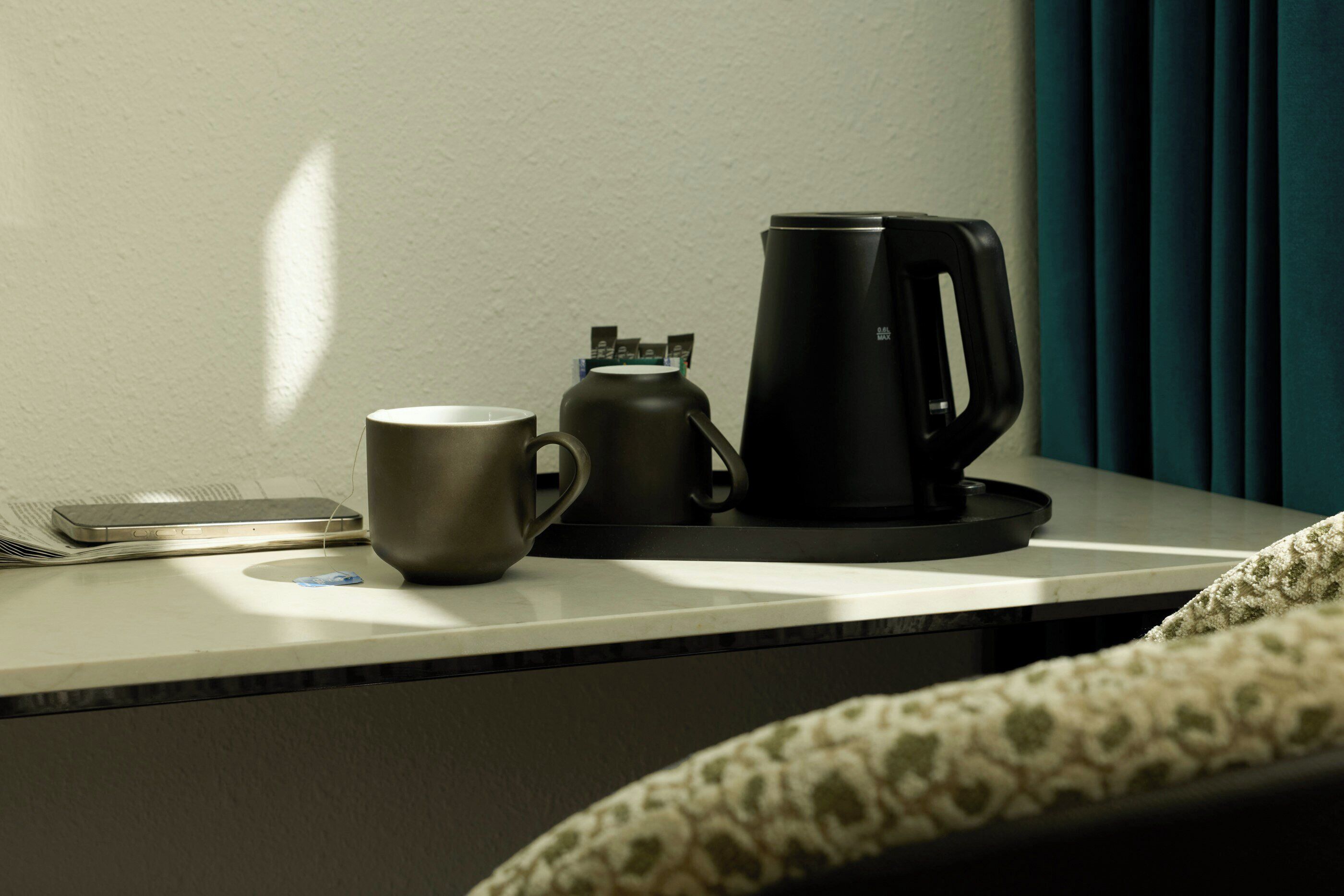 A table with a coffee maker, a mug, and a smartphone.
