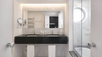 Een moderne badkamer met twee wastafels, een grote spiegel en een douche met glazen wanden.