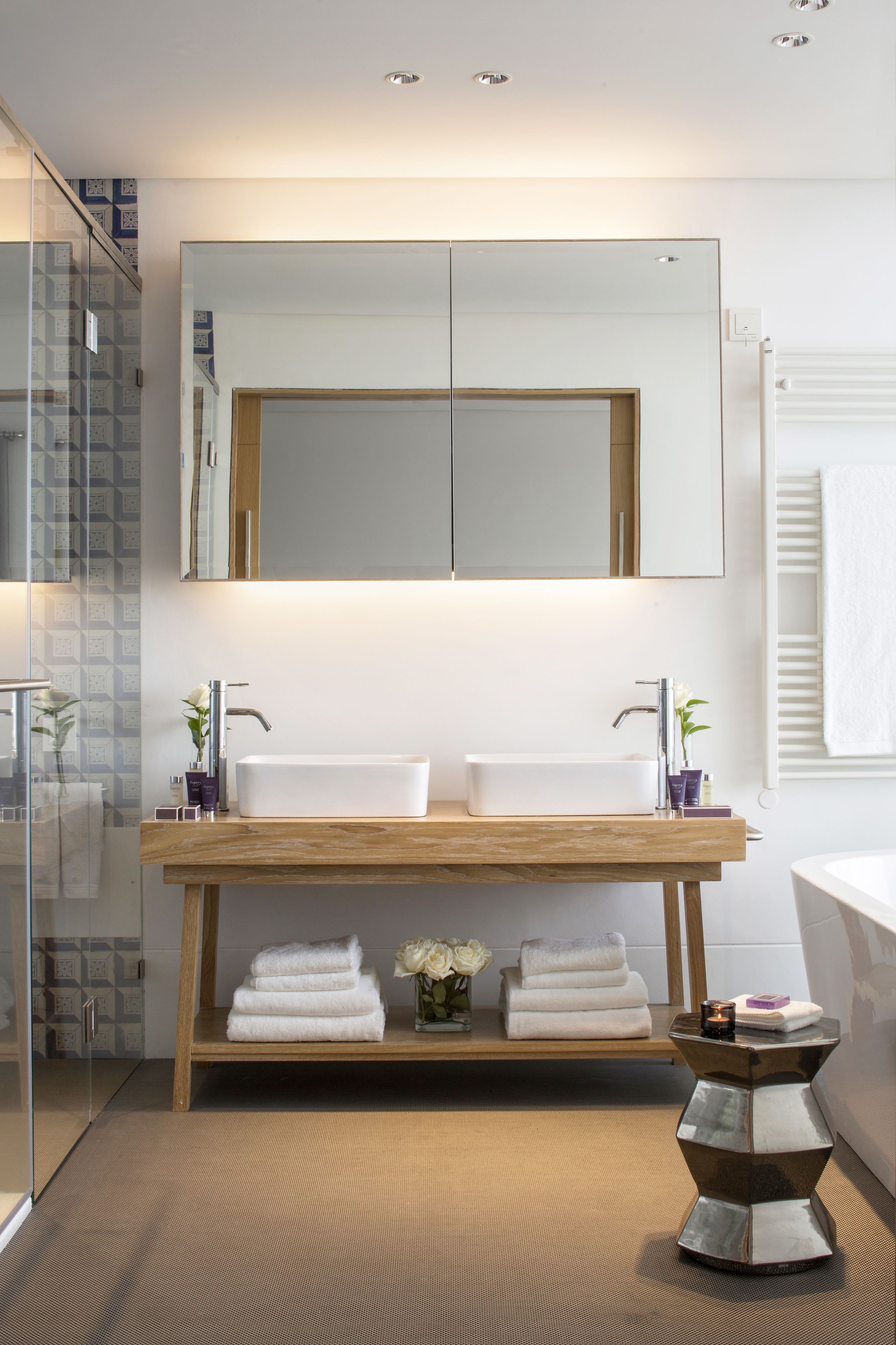 Un baño moderno con lavamanos doble, un espejo grande y un mueble de tocador de madera.