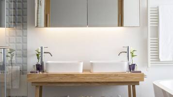 Un baño moderno con lavamanos doble, un espejo grande y un mueble de tocador de madera.