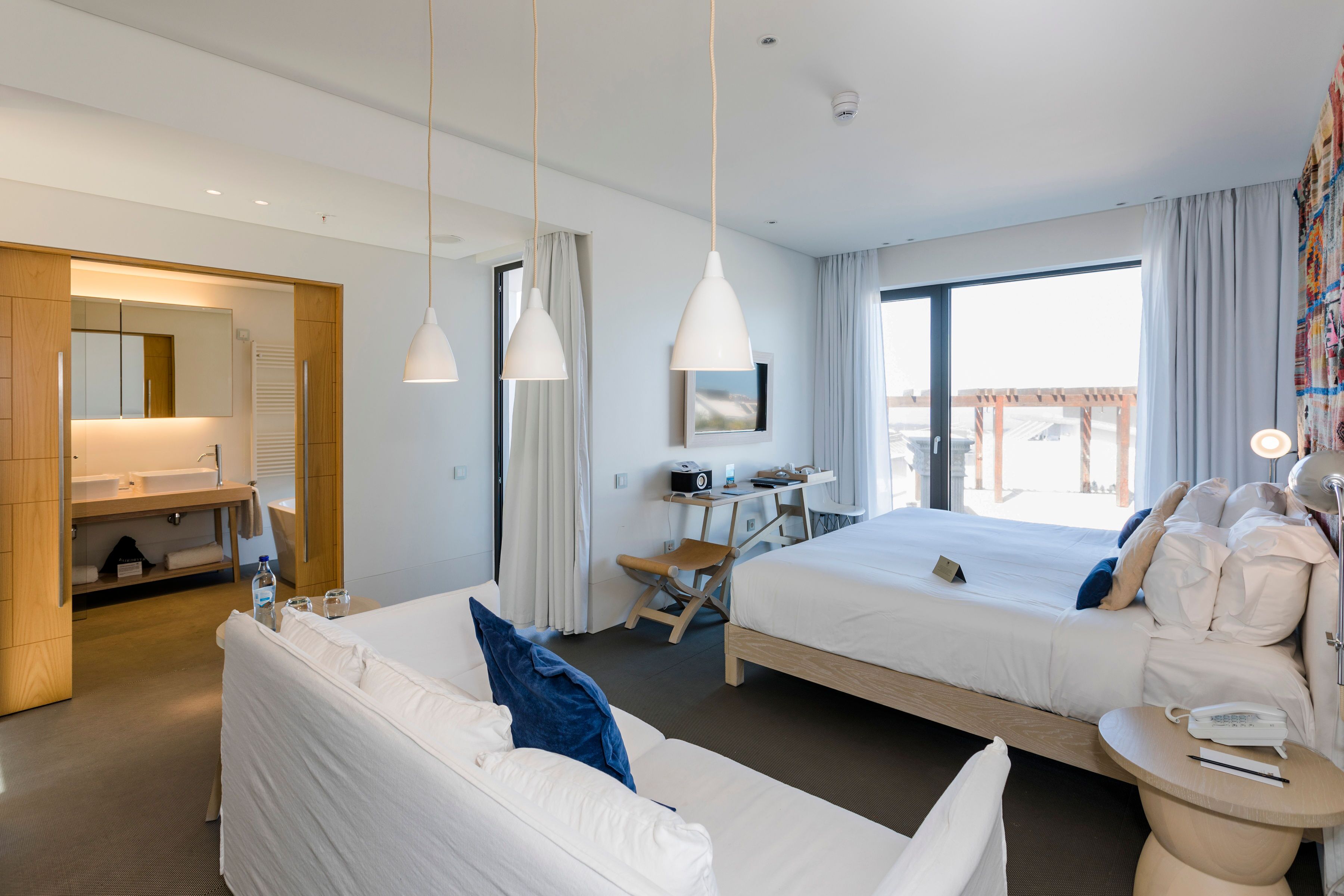 Una habitación de hotel moderna con dos camas, un escritorio, una silla y un ventanal grande.