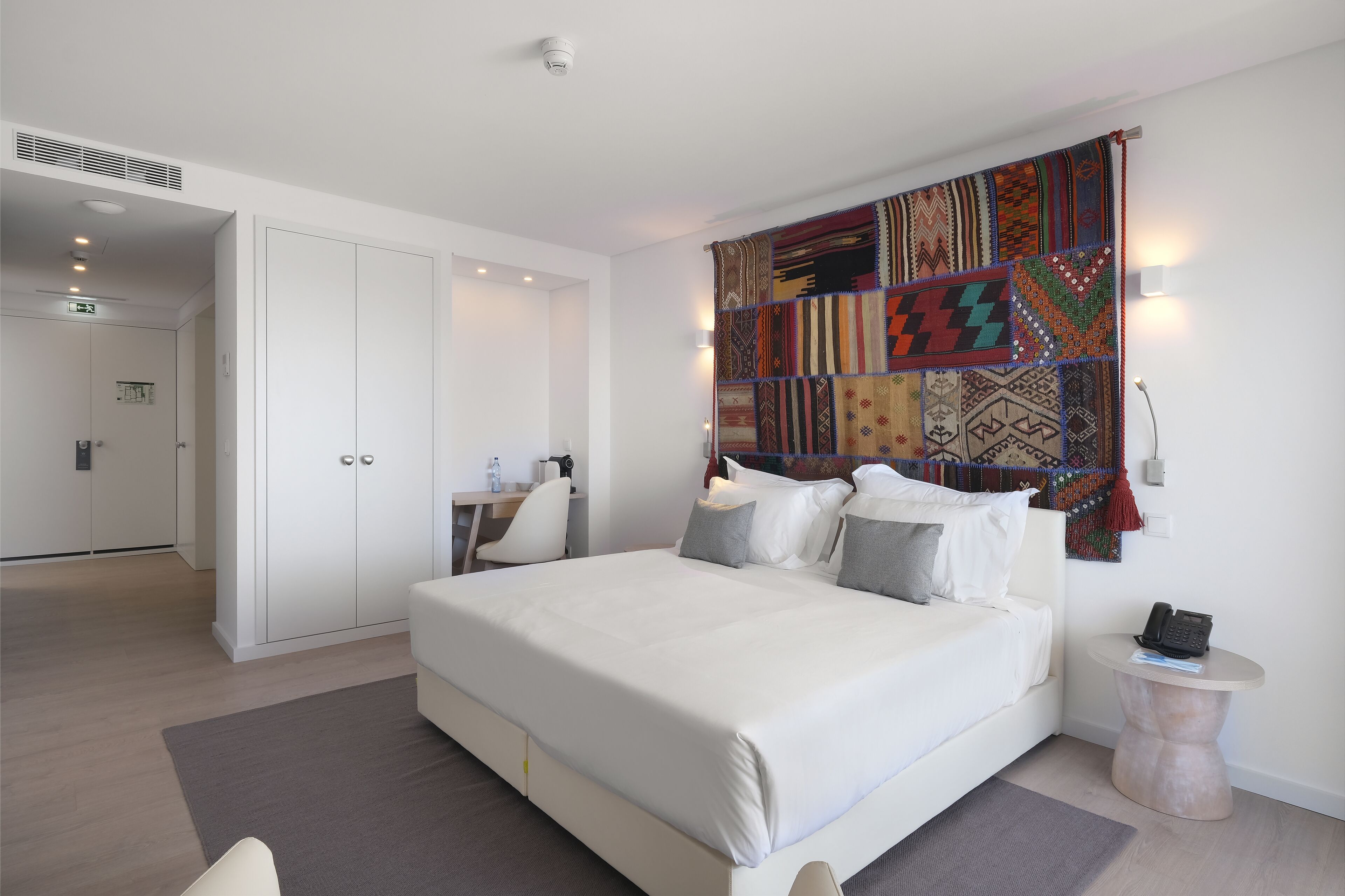 Un dormitorio moderno con una cama grande, un escritorio y un armario.