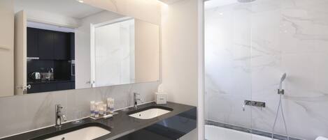 A modern bathroom with two sinks, a large mirror, and a glass-enclosed shower area.