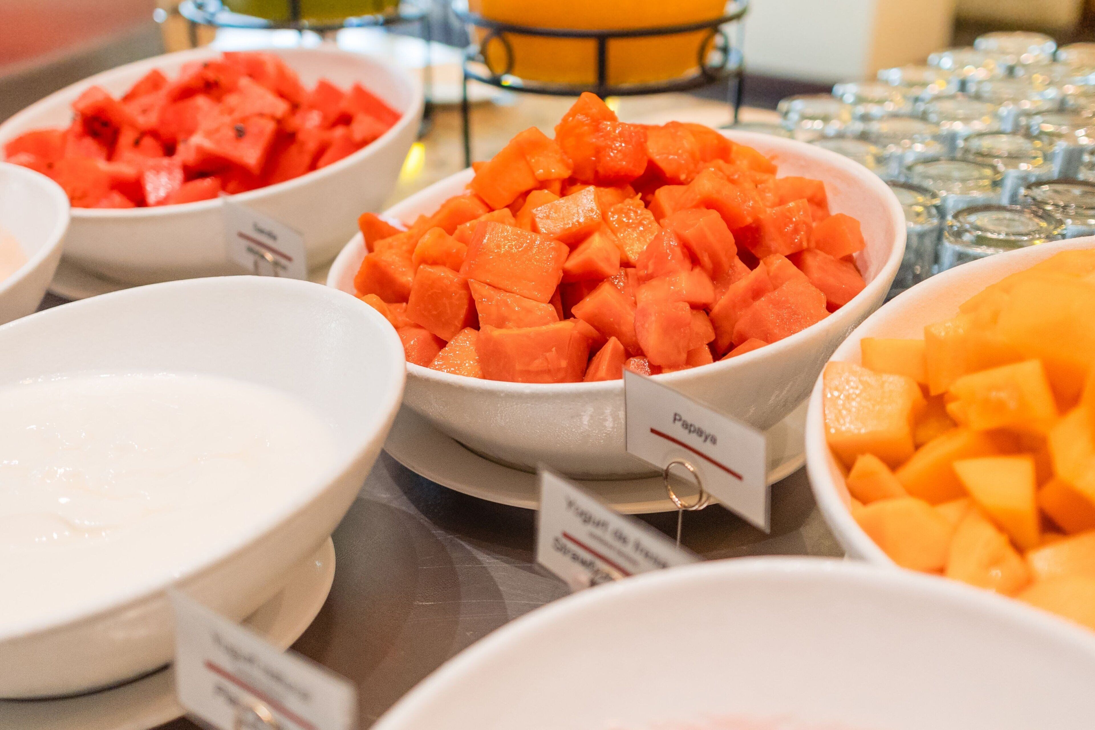Un bufé con diversos platos, incluyendo papaya y melón.