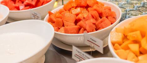 Un bufé con diversos platos, incluyendo papaya y melón.