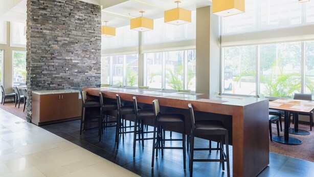 A modern kitchen with a stone accent wall, bar stools, and large windows. -  Courtyard by Marriott Ciudad del Carmen Campeche (Ciudad del Carmen)