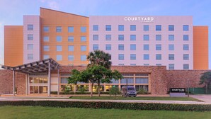 A Courtyard by Marriott hotel with a modern design, featuring a brick facade, multiple floors, and a covered entrance area. -  Courtyard by Marriott Ciudad del Carmen Campeche (Ciudad del Carmen)