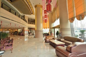 Eine geräumige Lobby mit hohen Decken, einer zentralen Säule und Sitzbereichen.