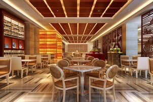Un restaurante con una decoración moderna, que cuenta con un área de comedor central con mesas y sillas redondas, un techo con diseño y una zona de bar con mostrador y estanterías.