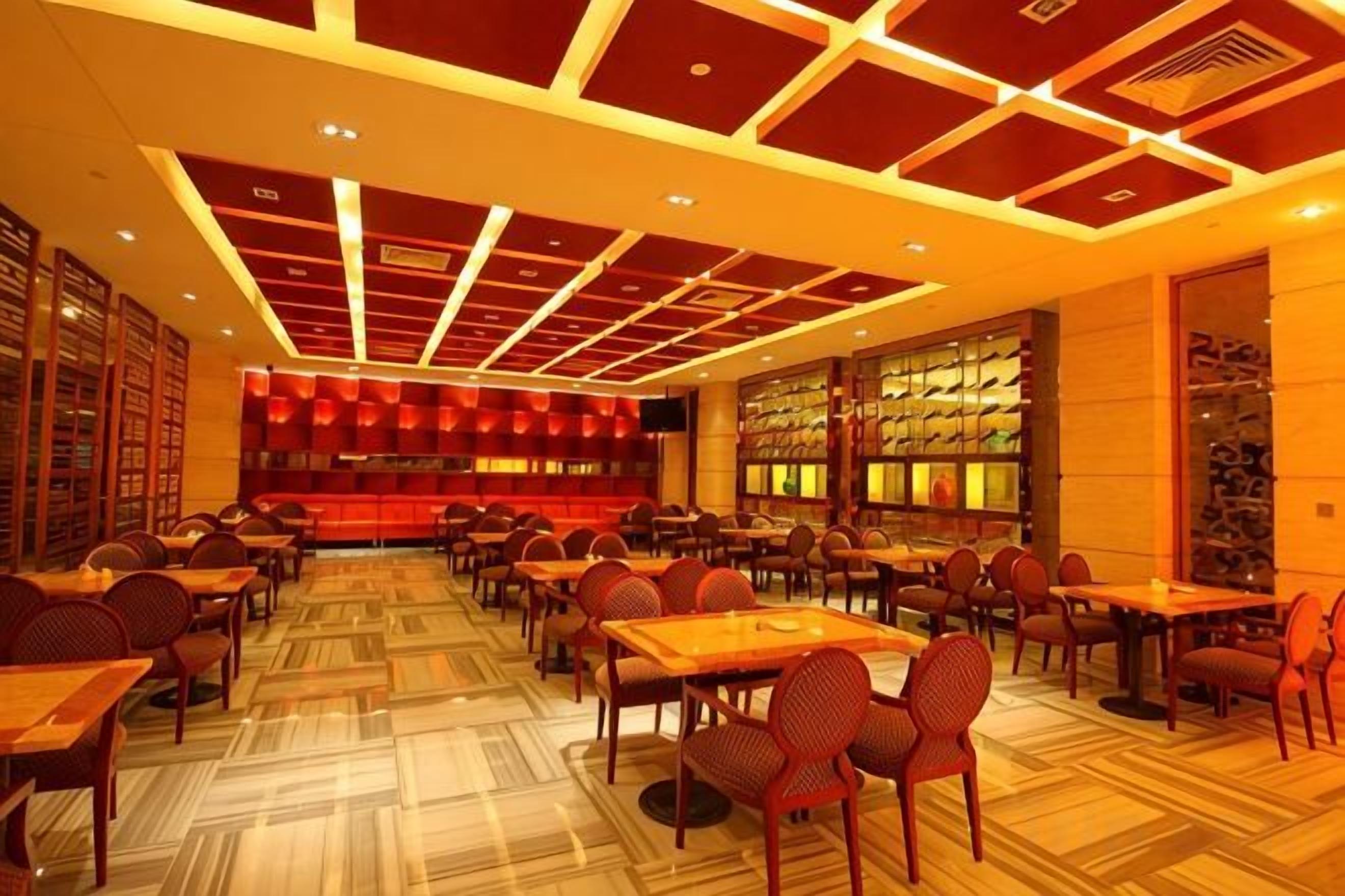 A spacious restaurant with high ceilings and a patterned floor, featuring multiple dining tables and chairs.