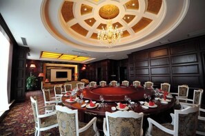 A conference room with a round table, chairs, and a chandelier. - Jinsheng Hotel (Nantong)