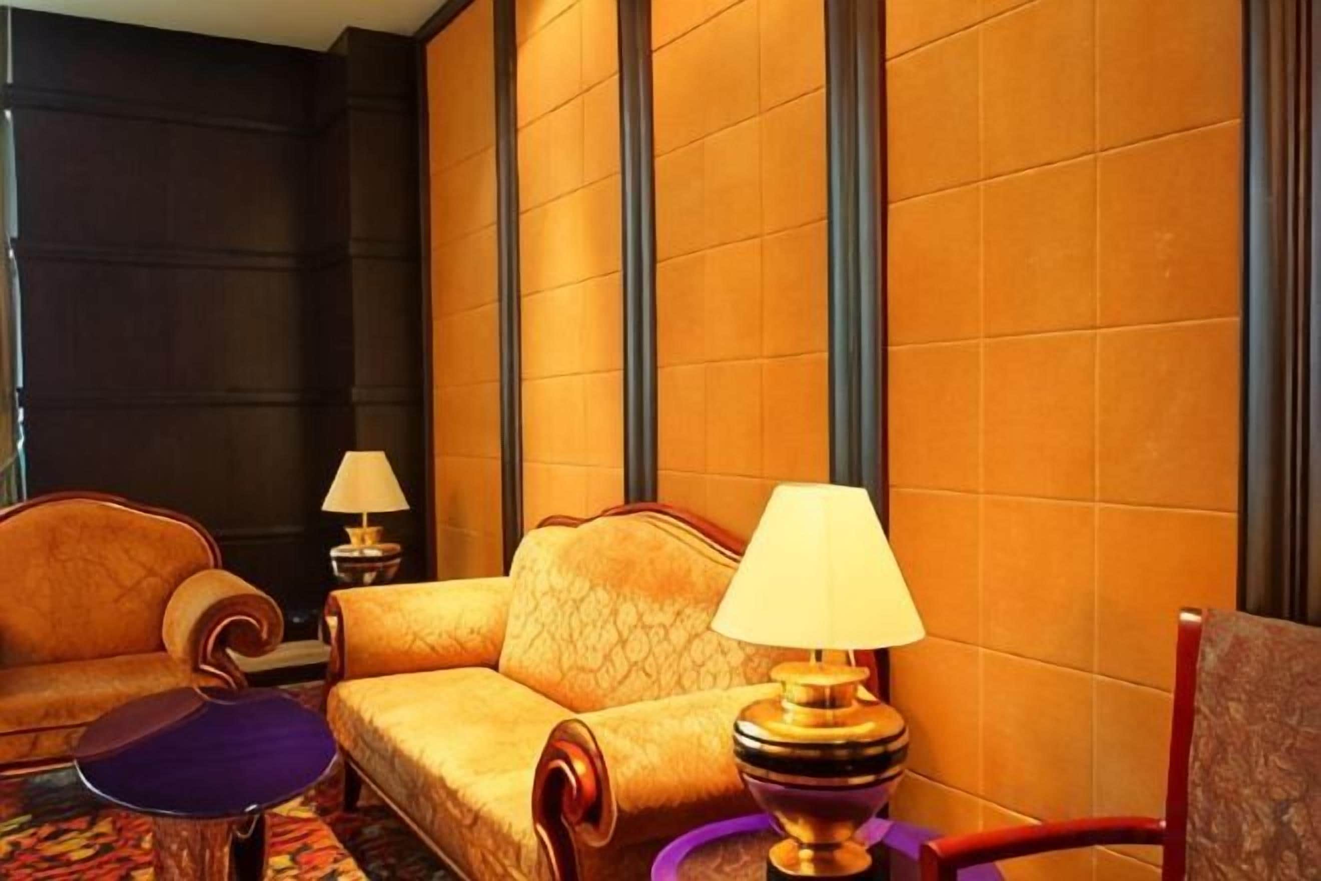 Una habitación de hotel con sofá, una mesita, una lámpara y una silla.