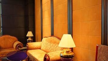 Una habitación de hotel con sofá, una mesita, una lámpara y una silla.