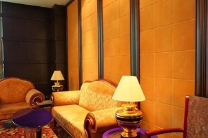 Una habitación de hotel con sofá, una mesita, una lámpara y una silla.