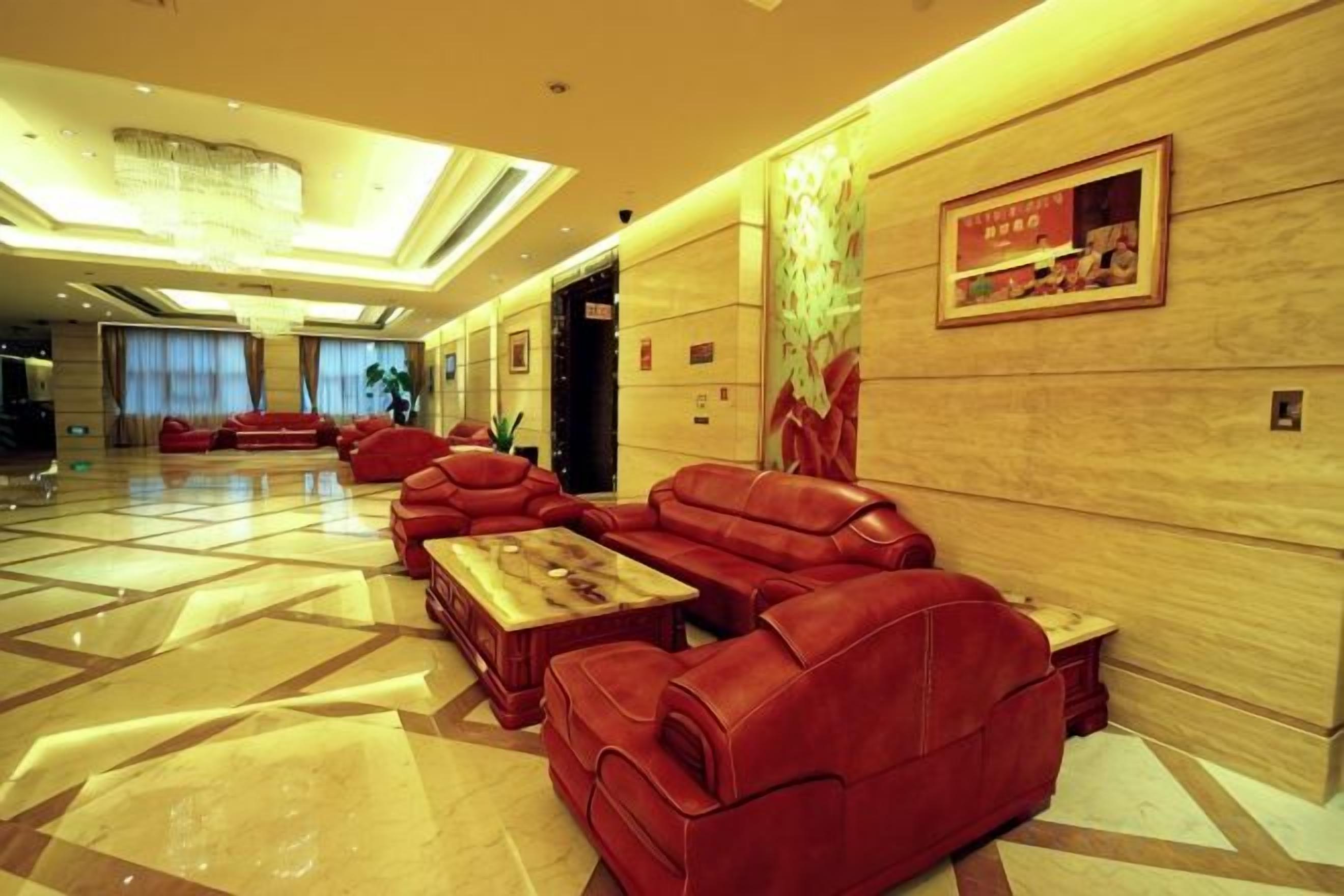 A spacious lobby with leather sofas, a coffee table, and a chandelier.