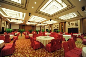 A banquet hall with round tables, red chairs, and a patterned carpet. - Jinsheng Hotel (Nantong)