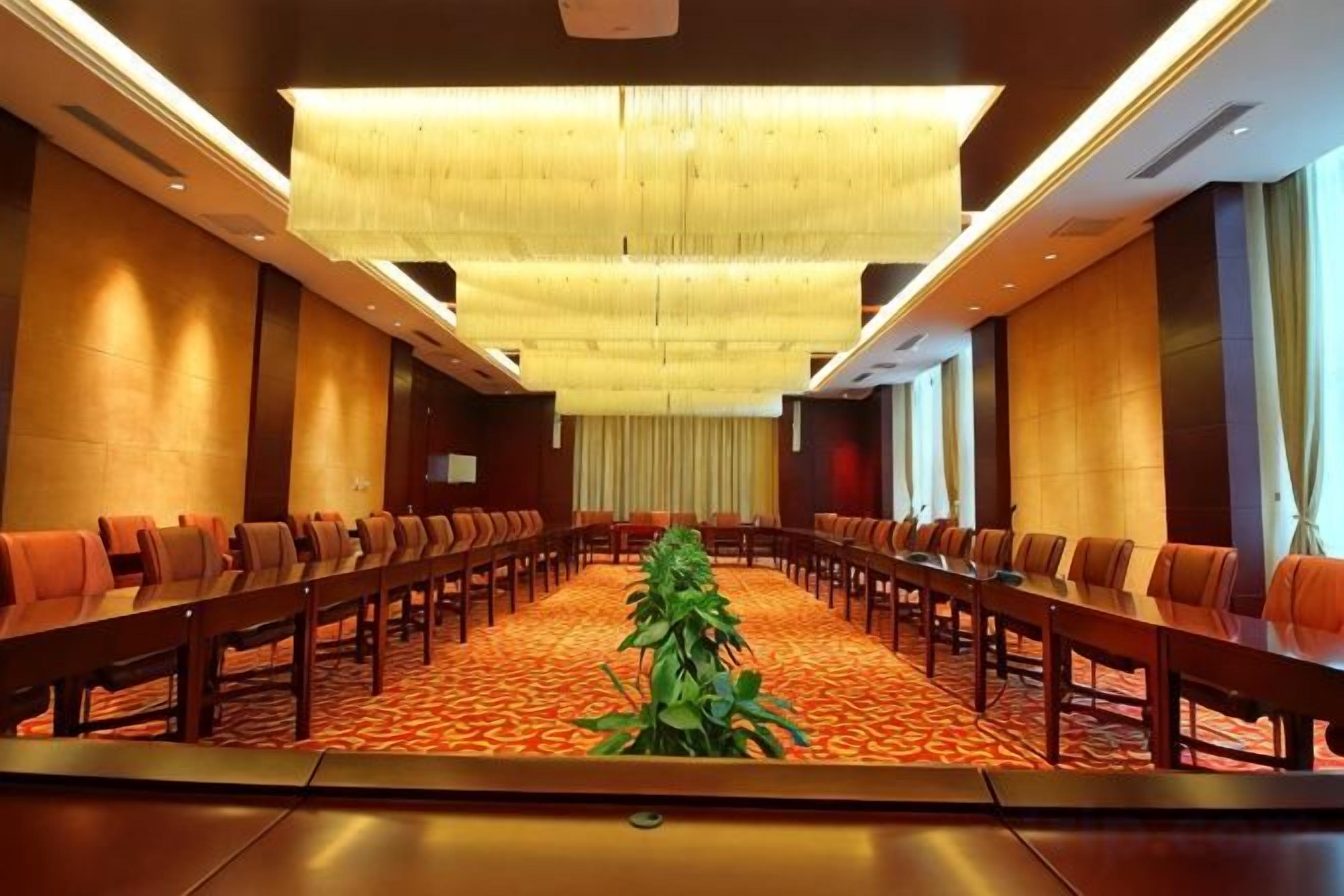 A conference room with a long table, multiple chairs, and a carpeted floor.