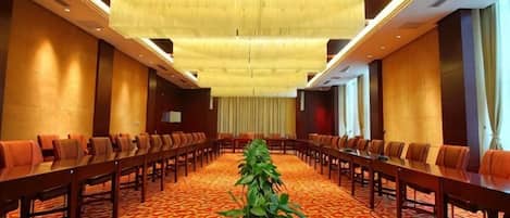 A conference room with a long table, multiple chairs, and a carpeted floor.