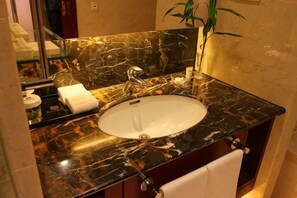 A bathroom with a marble sink, mirror, and a towel rack. - Jinsheng Hotel (Nantong)