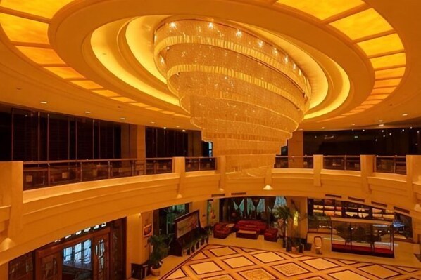A multi-level hotel lobby with a large chandelier, a central seating area, and a high ceiling.
