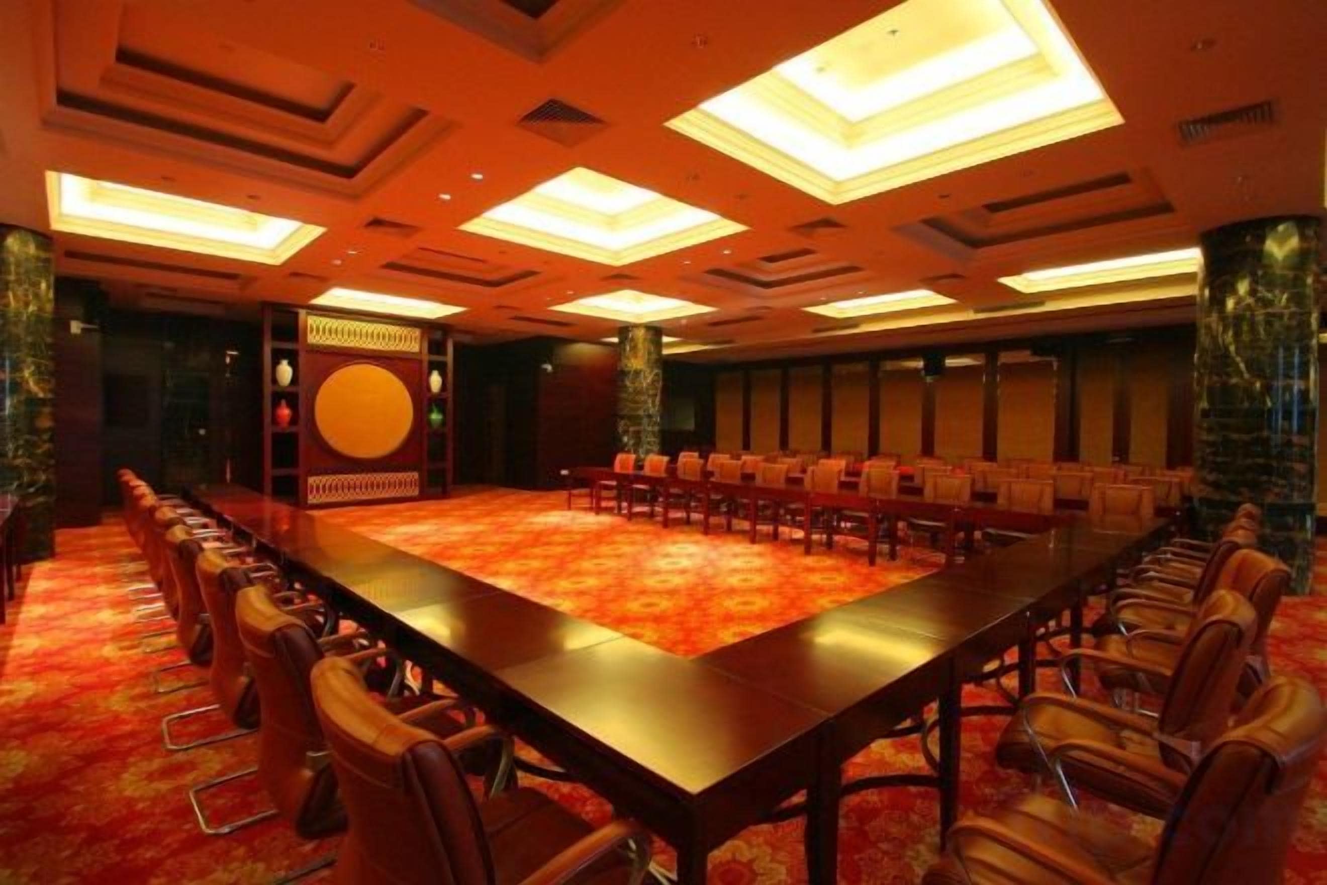 A conference room with a long table and chairs, a patterned carpet, and a decorative wall.