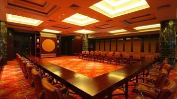 A conference room with a long table and chairs, a patterned carpet, and a decorative wall.