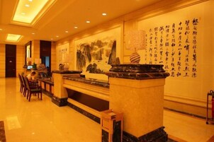 Un vestíbulo de hotel con mostrador de recepción, zona de estar y una pared con caligrafía.