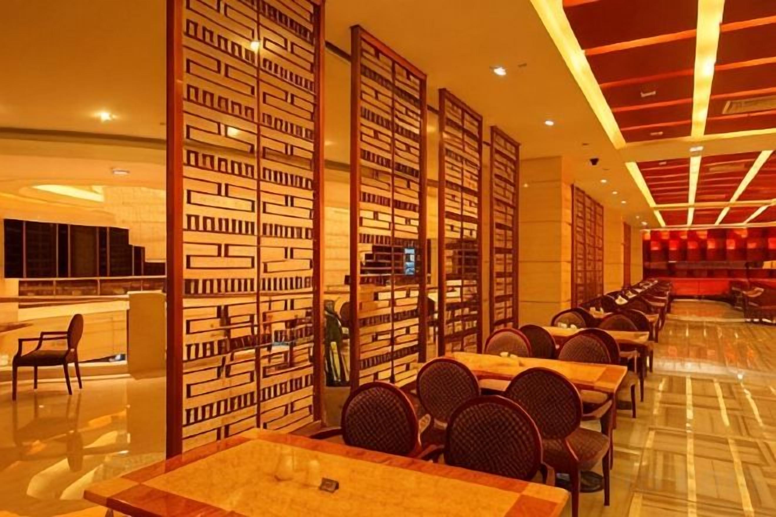 Un vestíbulo de hotel con una larga recepción, varias zonas de estar y una pared decorativa con paneles verticales.