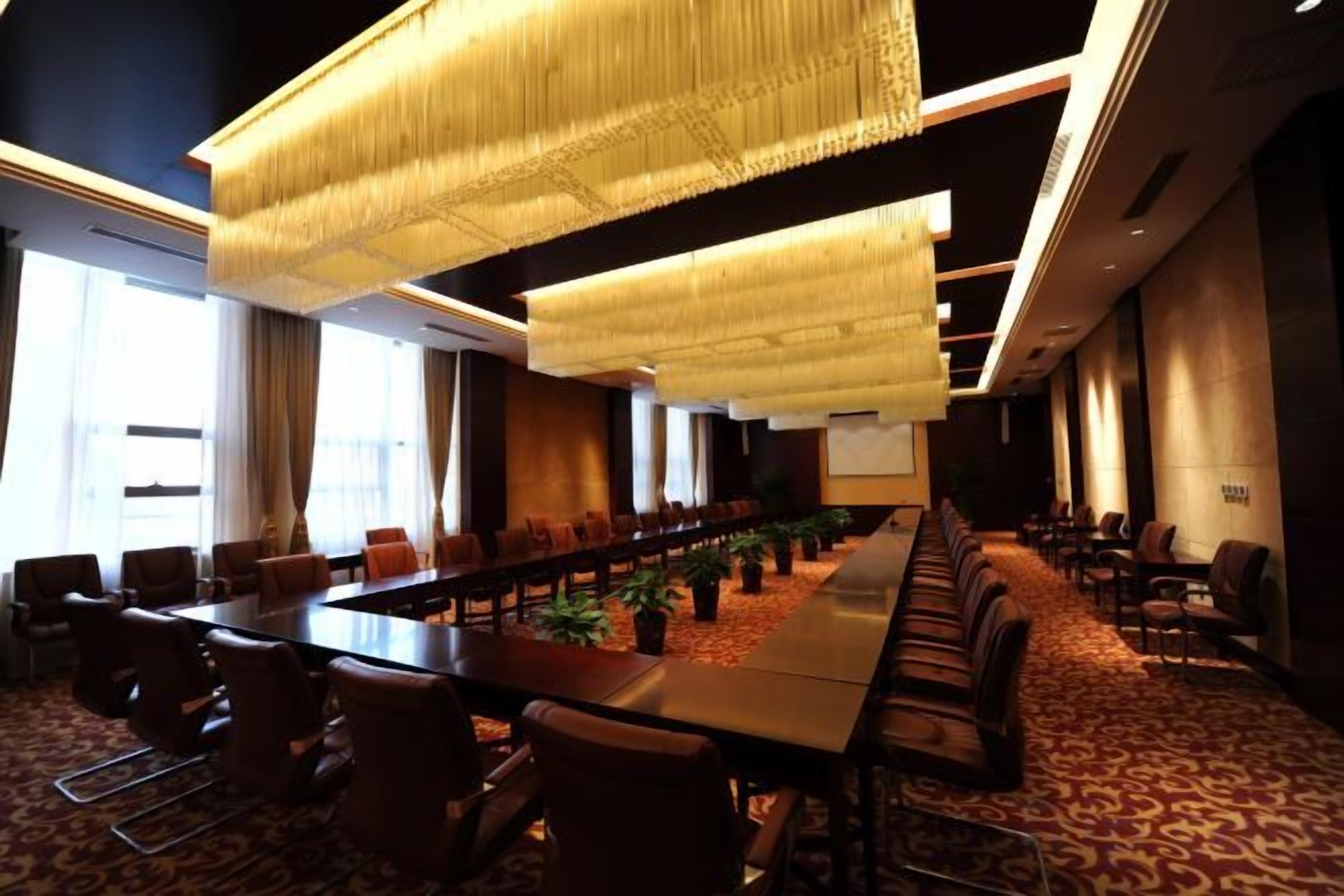 Un salón de conferencias con una larga mesa, sillas y una pantalla para proyector.