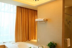 Une salle de bain équipée d’une baignoire, d’une douche, d’un porte-serviettes et d’une fenêtre avec des rideaux.