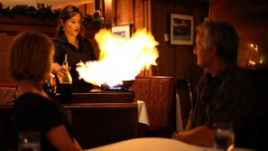 A restaurant with a bar area where a bartender is performing a flaming trick. - Convict Lake Resort (Mammoth Lakes)