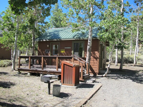 A small cabin with a green roof, a wooden deck, and a sign indicating it is a campground. - Convict Lake Resort (Mammoth Lakes)