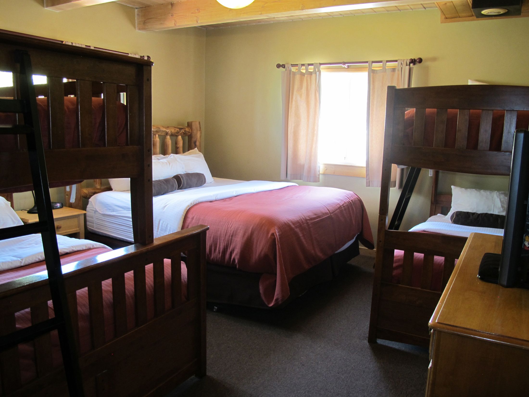 A room with bunk beds, a single bed, and a wooden desk.