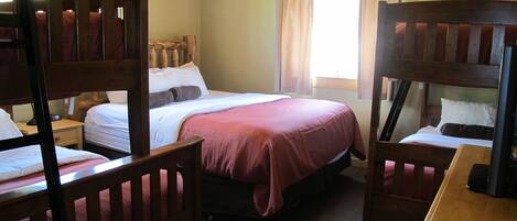 A room with bunk beds, a single bed, and a wooden desk.